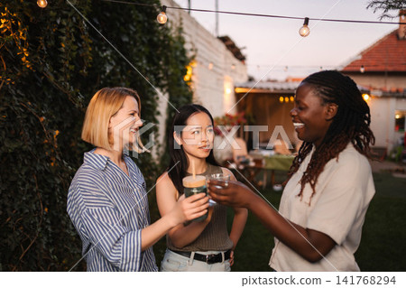 Multi ethnic women toasting drinks at backyard party Multi ethnic women toasting drinks at backyard party 141768294