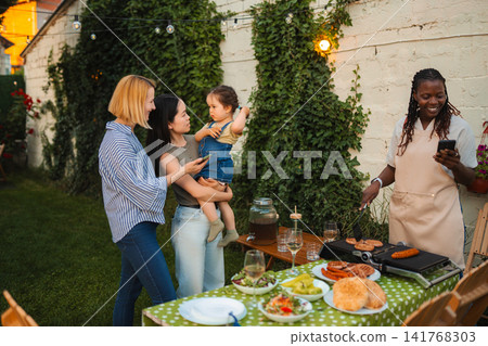 Multi ethnic friends enjoying backyard barbecue party with baby 141768303