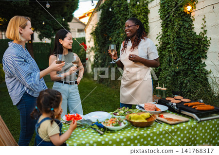 Diverse friends enjoying backyard barbecue party with food and drinks 141768317