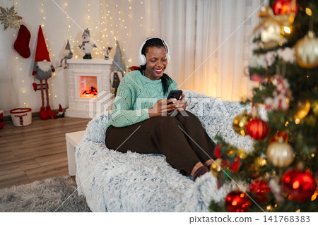 Woman relaxing at home listening to music during Christmas holiday Woman relaxing at home listening to music during Christmas holiday 141768383