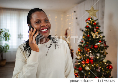Black woman smiling talking on phone during holidays 141768389