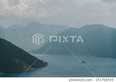 Panoramic view of Perast, the Bay of Kotor and the famous islands in Montenegro. Dramatic mountains surround the calm Adriatic waters on a hazy summer day Panoramic view of Perast, the Bay of Kotor and the famous islands in Montenegro. Dramatic mountains surround the calm Adriatic waters on a hazy summer day 141768459