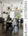 Bright contemporary cafe interior with stylish furniture, large windows, and decorative lighting. Cozy hospitality space prepared for guests in a modern coffee shop 141768541