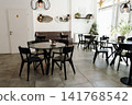 Bright contemporary cafe interior with stylish furniture, large windows, and decorative lighting. Cozy hospitality space prepared for guests in a modern coffee shop 141768542