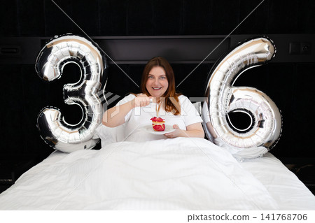 Happy 36th birthday celebration in bed with balloons and dessert Happy 36th birthday celebration in bed with balloons and dessert 141768706