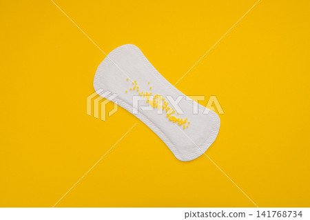 Sanitary Pad with Yellow Beads Symbolising Urinary Leakage on Yellow Background Sanitary Pad with Yellow Beads Symbolising Urinary Leakage on Yellow Background 141768734