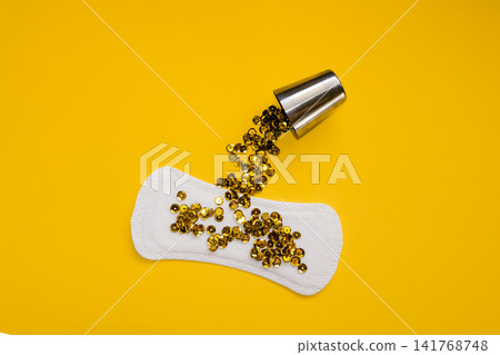 Sanitary Pad with Gold Sequins Pouring from Metal Cup, Heavy Urinary Incontinence Concept Sanitary Pad with Gold Sequins Pouring from Metal Cup, Heavy Urinary Incontinence Concept 141768748
