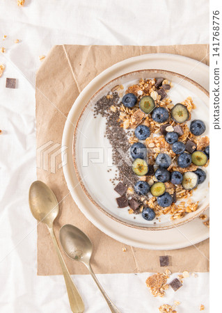 Healthy yogurt bowl with fresh blueberries, granola, and chia seeds in a rustic ceramic dish for a nutritious, delicious morning meal Healthy yogurt bowl with fresh blueberries, granola, and chia seeds in a rustic ceramic dish for a nutritious, delicious morning meal 141768776