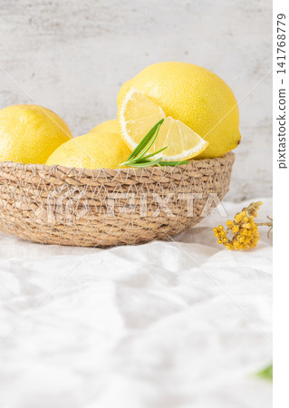 Fresh yellow lemons with rosemary sprigs in basket Fresh yellow lemons with rosemary sprigs in basket 141768779