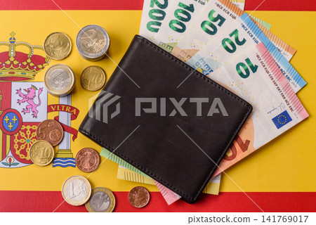 Spain, Spanish euro cash and cent coins against the background of the flag. Euro cash Spain, Spanish euro cash and cent coins against the background of the flag. Euro cash 141769017