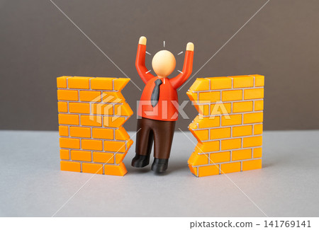 A businessman breaks down a wall. A breakthrough achievement at work. Breaking through to success. Breaking down the wall of misunderstanding with the government. A businessman breaks down a wall. A breakthrough achievement at work. Breaking through to success. Breaking down the wall of misunderstanding with the government. 141769141