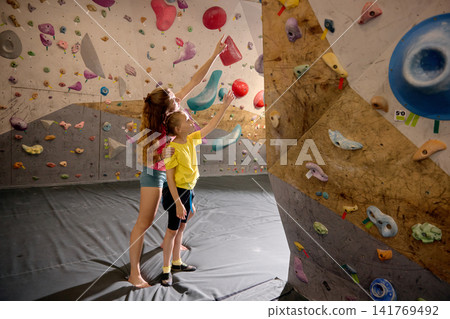 Female coach explaining climbing route to young girl before next indoor attempt Female coach explaining climbing route to young girl before next indoor attempt 141769492
