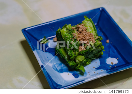 Sesame dressing on rape blossoms served on a blue square plate Sesame dressing on rape blossoms served on a blue square plate 141769575