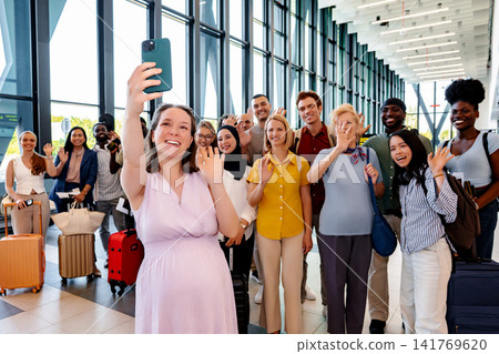 Pregnant woman taking selfie with diverse group of happy travelers in airport Pregnant woman taking selfie with diverse group of happy travelers in airport 141769620