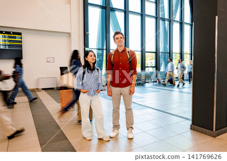 Young adult travelers navigating modern airport terminal building Young adult travelers navigating modern airport terminal building 141769626