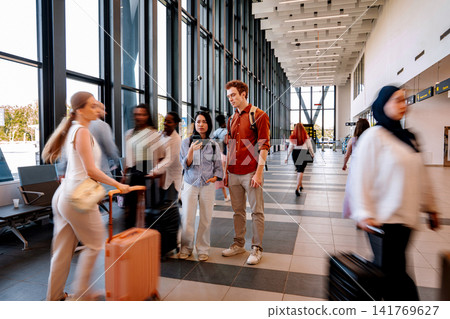 Travelers walking through modern airport during peak travel season 141769627