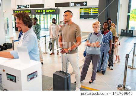 Diverse people waiting in line at airport check-in counter Diverse people waiting in line at airport check-in counter 141769643