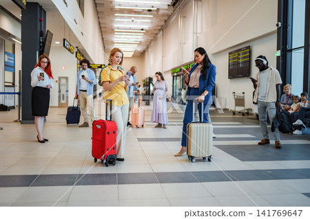 People waiting in airport terminal looking at smartphones People waiting in airport terminal looking at smartphones 141769647