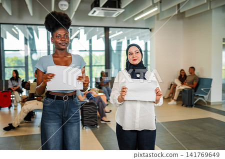 Two women holding blank signs welcoming arrivals at airport Two women holding blank signs welcoming arrivals at airport 141769649
