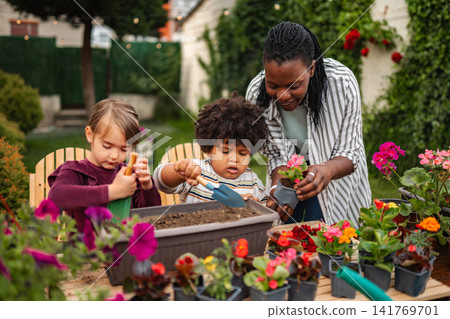 Black mother gardening with diverse children in backyard Black mother gardening with diverse children in backyard 141769701