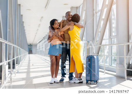 African American family of three group hugging at airport terminal 141769747
