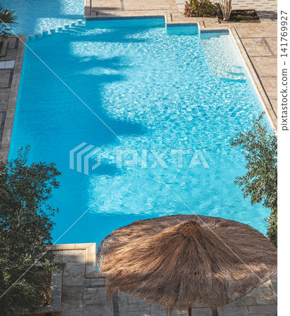 Sun umbrella near the pool in a hotel, a place to relax outdoors on vacation Sun umbrella near the pool in a hotel, a place to relax outdoors on vacation 141769927
