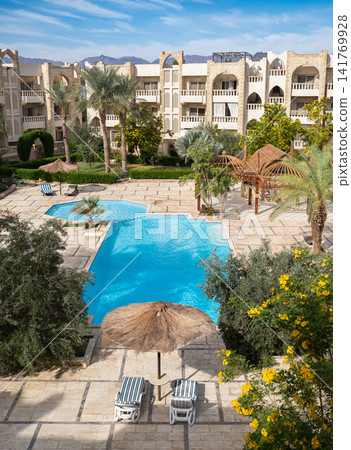Luxury tropical resort swimming pool and garden landscaping. Modern architecture with tropical palms Luxury tropical resort swimming pool and garden landscaping. Modern architecture with tropical palms 141769928