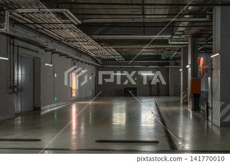 Empty Underground Parking Garage Corridor With Industrial Pipes, Concrete Floor and Reflections Empty Underground Parking Garage Corridor With Industrial Pipes, Concrete Floor and Reflections 141770010