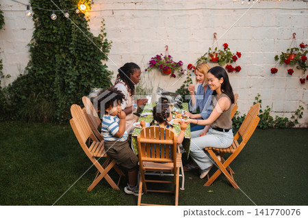 Multi ethnic family friends enjoying backyard summer dinner party Multi ethnic family friends enjoying backyard summer dinner party 141770076