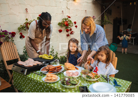 Diverse family enjoying backyard barbecue together with kids Diverse family enjoying backyard barbecue together with kids 141770085