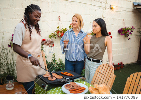 Friends grilling barbecue and drinking wine at backyard party Friends grilling barbecue and drinking wine at backyard party 141770089