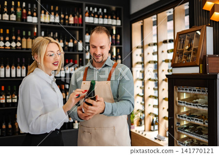 Sommelier assisting woman customer choosing wine in shop Sommelier assisting woman customer choosing wine in shop 141770121