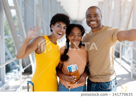Cheerful Black family posing for smartphone selfie at the airport Cheerful Black family posing for smartphone selfie at the airport 141770635