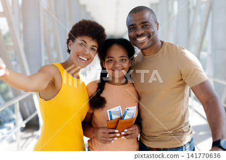 Close portrait of smiling Black family taking selfie in bright airport terminal Close portrait of smiling Black family taking selfie in bright airport terminal 141770636