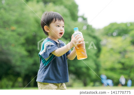 一個男孩在喝瓶裝茶 一個男孩在喝瓶裝茶 141770775
