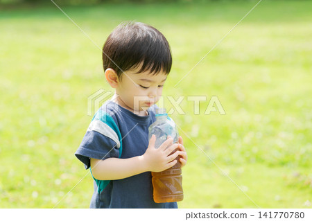 一個男孩在喝瓶裝茶 一個男孩在喝瓶裝茶 141770780