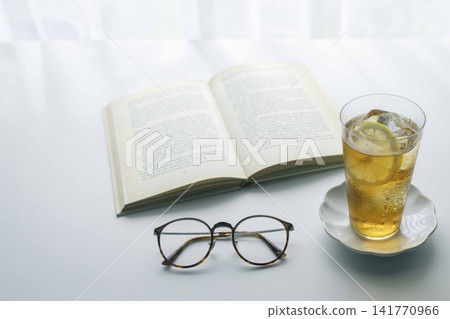 A relaxing reading time with lemon iced tea, a book, and glasses. A relaxing reading time with lemon iced tea, a book, and glasses. 141770966