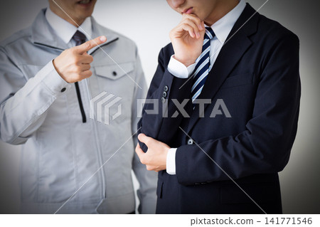 A young man in a business suit and a middle-aged man in work clothes, both looking dejected after being scolded. A young man in a business suit and a middle-aged man in work clothes, both looking dejected after being scolded. 141771546