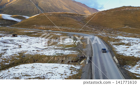 Aerial view of car driving along Georgian Military Road highway through snowy mountain pass in early winter for Caucasus road trip and freedom travel destination concept Aerial view of car driving along Georgian Military Road highway through snowy mountain pass in early winter for Caucasus road trip and freedom travel destination concept 141771610