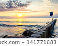 A picturesque sunset on the sea shore with a breakwater 141771683