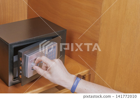 Man hand turns knob opening metal safe box door inside wooden wardrobe cabinet after unlocking mechanism for valuable asset retrieval concept Man hand turns knob opening metal safe box door inside wooden wardrobe cabinet after unlocking mechanism for valuable asset retrieval concept 141772010