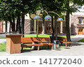 Wooden park benches next to a trash bin and decorative street lamps. 141772040