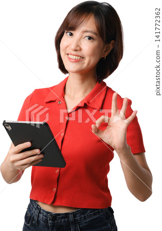 Asian woman holding tablet in red shirt smiling and making okay gesture, isolated portrait for communication, technology and business concept Asian woman holding tablet in red shirt smiling and making okay gesture, isolated portrait for communication, technology and business concept 141772362