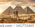 Famous Giza Pyramids stand behind the Great Sphinx under a dramatic sunset desert sky, Egypt. 141772405