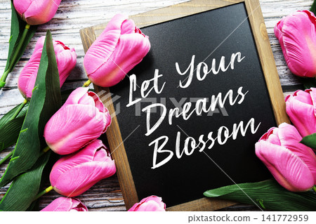Let Your Dreams Blossom text written on notepad with flower decoration on wooden background Let Your Dreams Blossom text written on notepad with flower decoration on wooden background 141772959