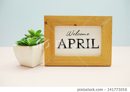 wooden frame with text "WELCOME APRIL" and small artificial plant wooden frame with text "WELCOME APRIL" and small artificial plant 141773058