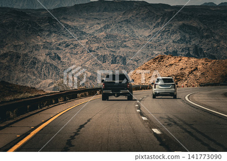 A roadside scene of a highway and convoy of cars running through the vast desert landscape of Arizona. A roadside scene of a highway and convoy of cars running through the vast desert landscape of Arizona. 141773090
