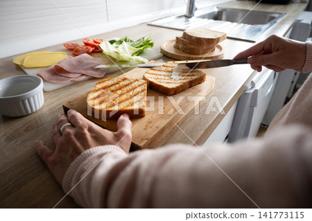 Preparing a grilled ham and cheese sandwich Preparing a grilled ham and cheese sandwich 141773115
