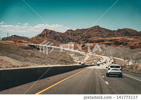 A roadside scene of a highway and convoy of cars running through the vast desert landscape of Arizona. A roadside scene of a highway and convoy of cars running through the vast desert landscape of Arizona. 141773117