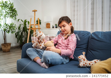 Little girl playing with stuffed animals on sofa at home Little girl playing with stuffed animals on sofa at home 141773452
